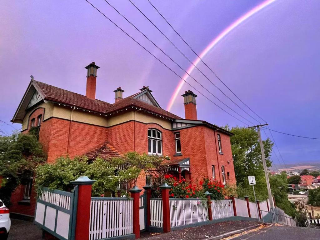 a rainbow in the sky above a brick house at Elsmere Heritage Gardens & Accom in Launceston