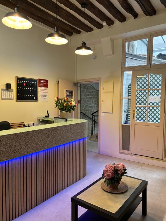 un hall d'entrée avec un comptoir avec des fleurs sur une table dans l'établissement Hôtel Des Fontaines, à Paris