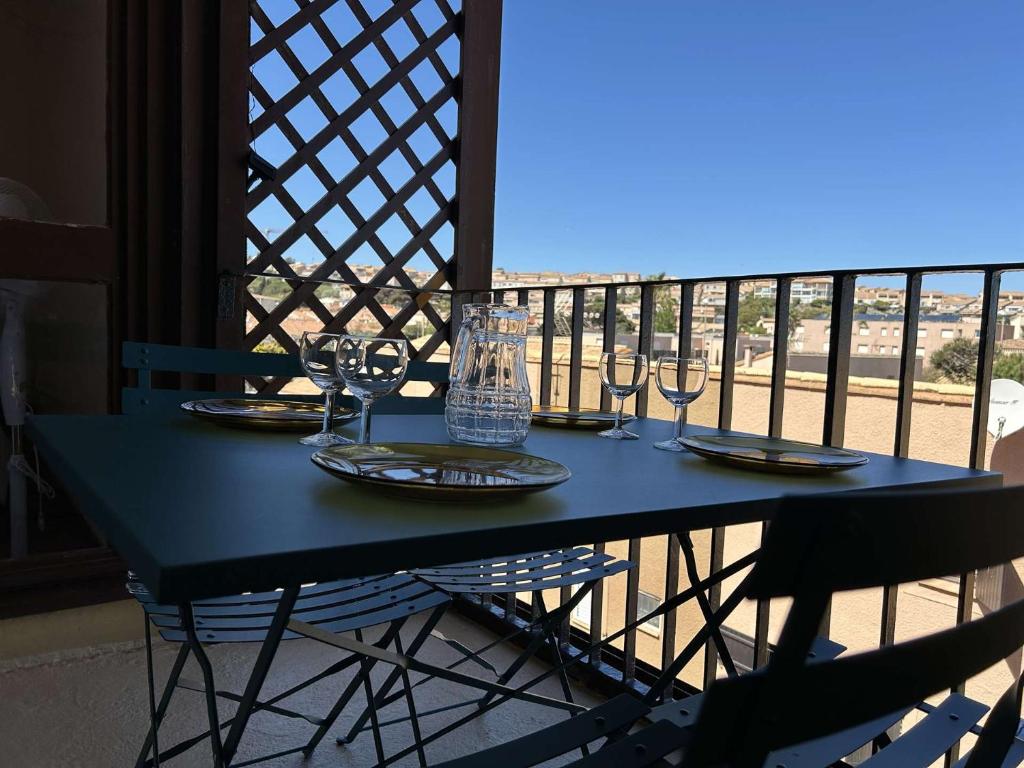 un tavolo blu con bicchieri da vino sul balcone di SP350-B202 Appartement 2 pièces cabine SAINT PIERRE LA MER a Saint Pierre La Mer