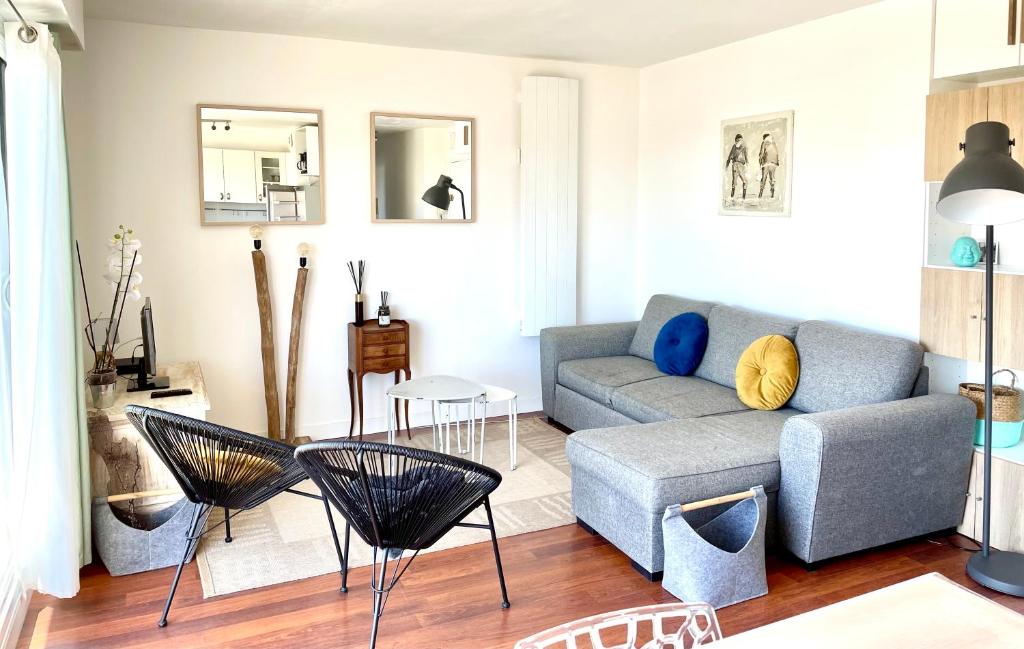 a living room with a couch and a table and chairs at Appartement et terrasse Port du Pouliguen in Le Pouliguen