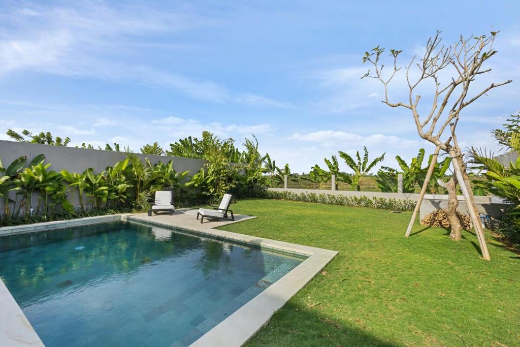 a swimming pool in the yard of a house at Villa Luxfield - Peaceful minimalist 2BR villa with Big garden and Views in Cemagi