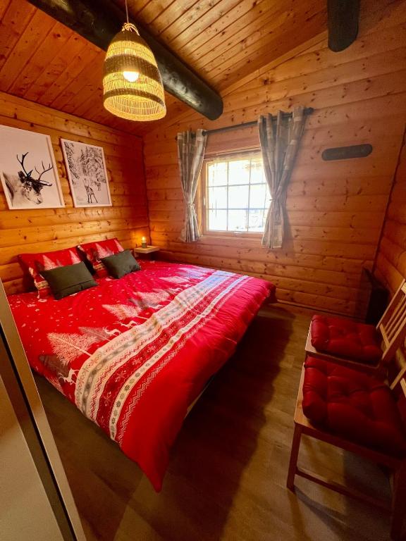 une chambre avec un grand lit rouge dans une cabane en rondins dans l'établissement Le cocon de La Bresse, à La Bresse