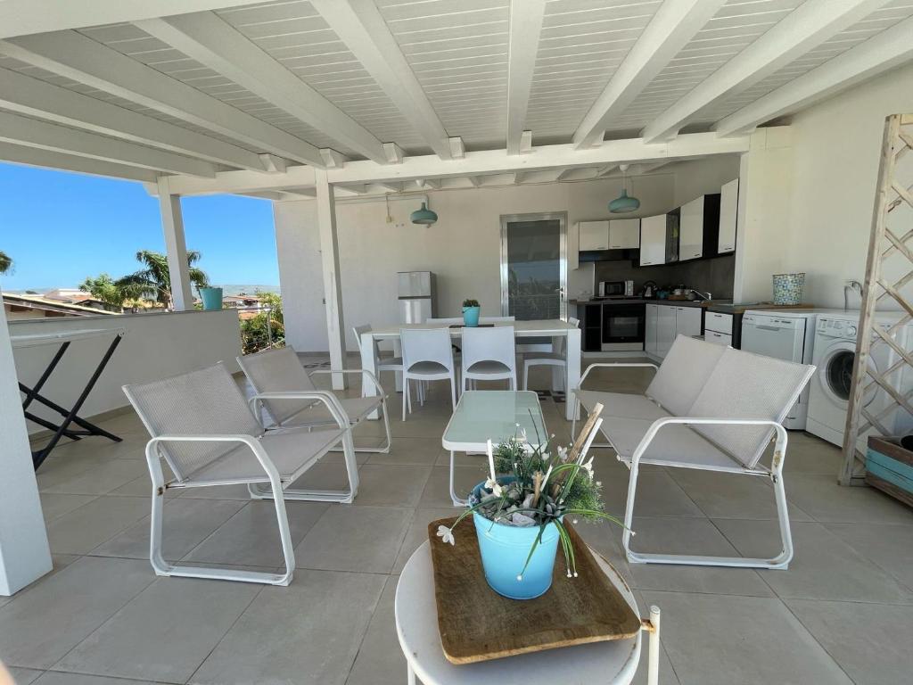 Villa Eraclea في سان ليون: فناء مع كراسي وطاولات بيضاء ومطبخ