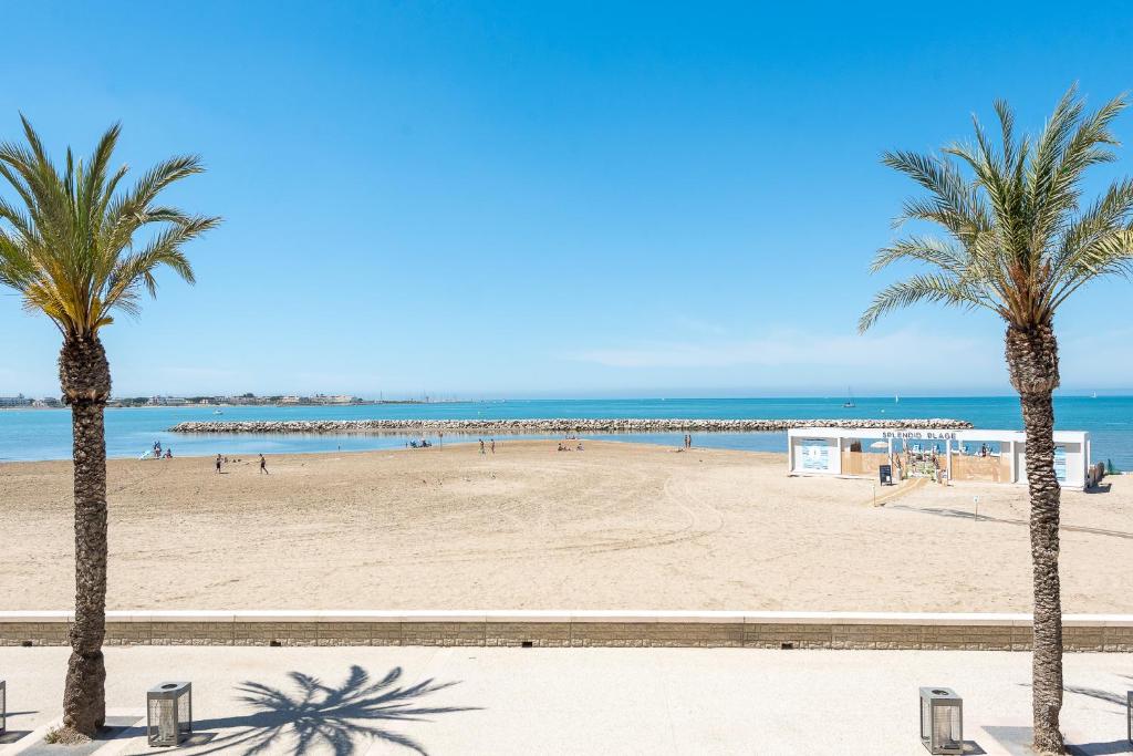 une plage avec des palmiers et l'océan dans l'établissement Appartement Vue Exceptionnelle 2Ch - Sur La Plage, au Grau-du-Roi
