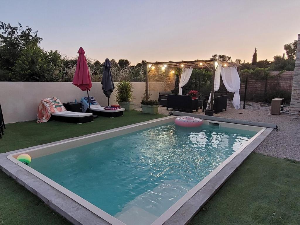 une piscine dans une cour avec un parasol dans l'établissement Maison de vacances avec piscine près de Montpellier, à Saint-Drézéry