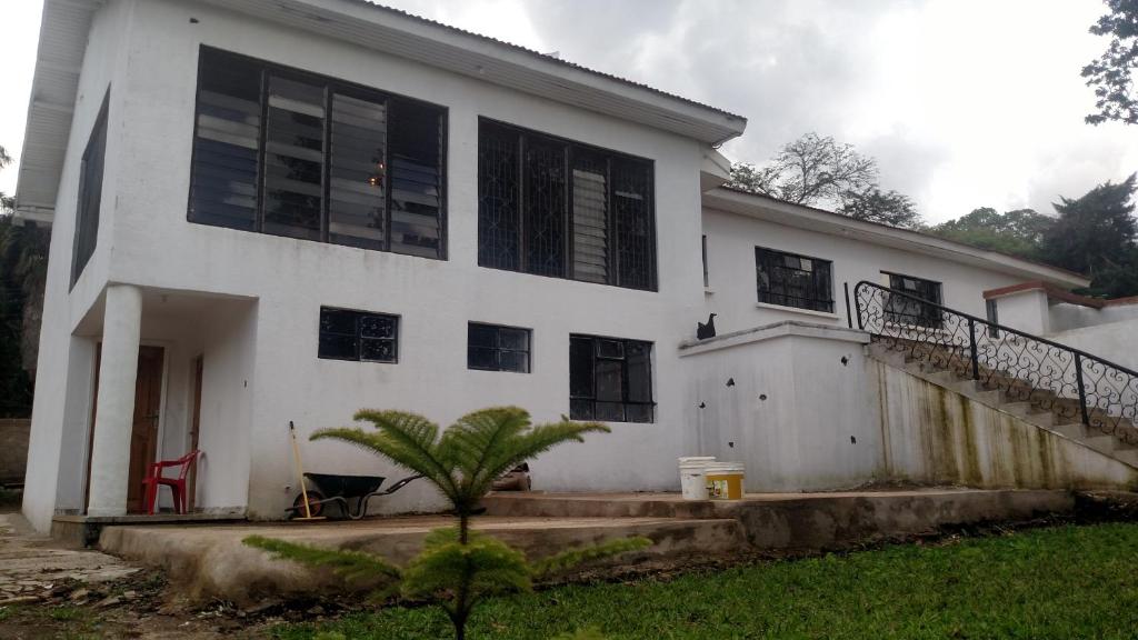 a white house with black windows and a staircase at Eden Hill Villas - Njiro, Arusha in Nkunjila