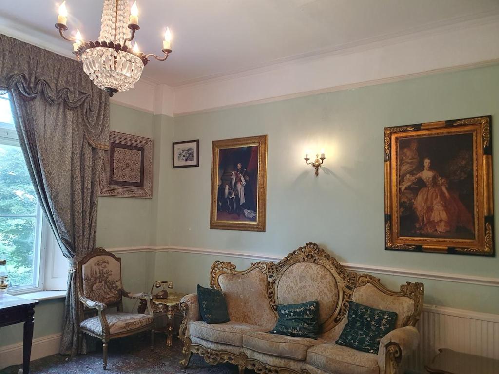 a living room with two chairs and a couch and a chandelier at Country Manor House in Higham
