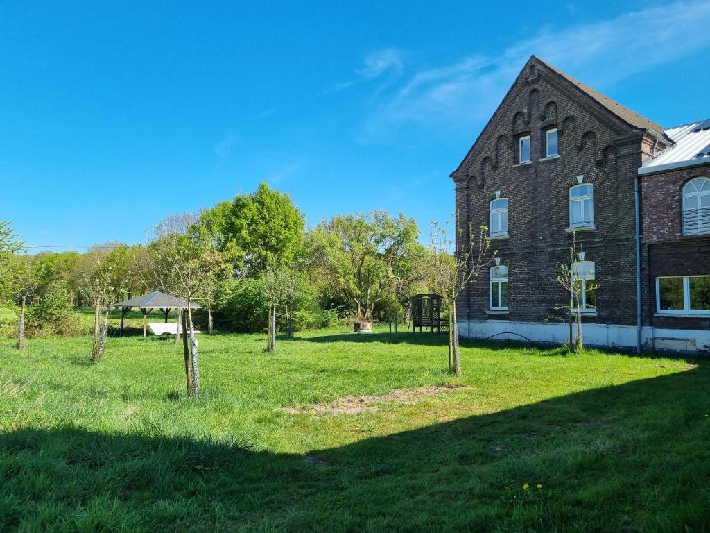 an old brick building with a yard with trees at Gartenblick im Gutshaus - Ferienwohnung in Kevelaer