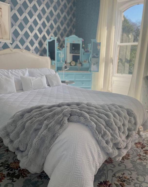 a blue bedroom with a bed with a blanket at Gardenvale Manor House B&B in Stranocum