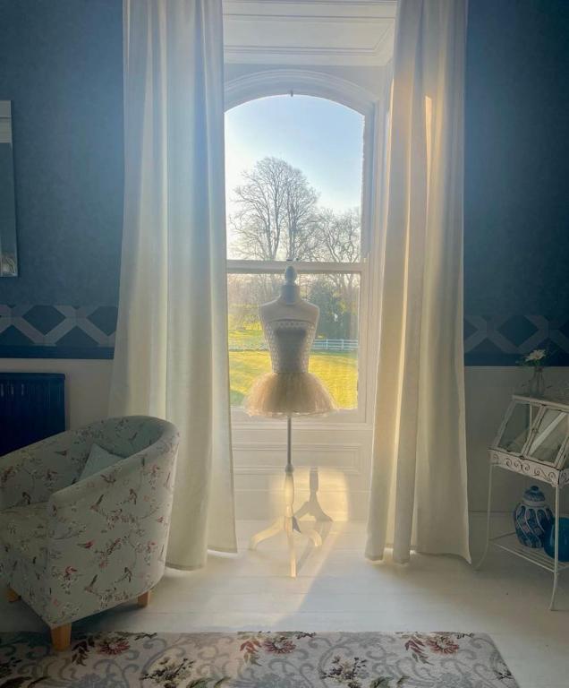 a room with a window with a lamp and a chair at Gardenvale Manor House B&B in Stranocum