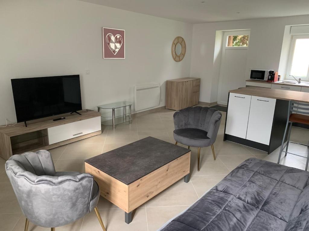 Il comprend un salon doté d'une télévision, de chaises et d'une table. dans l'établissement Appartement bien placé, à Hermonville