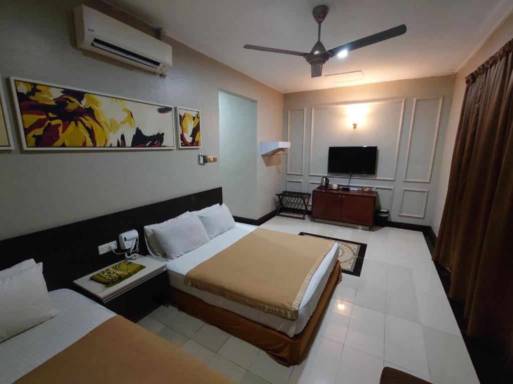 a hotel room with two beds and a television at Najmi Inn Hotel in Kampong Burok