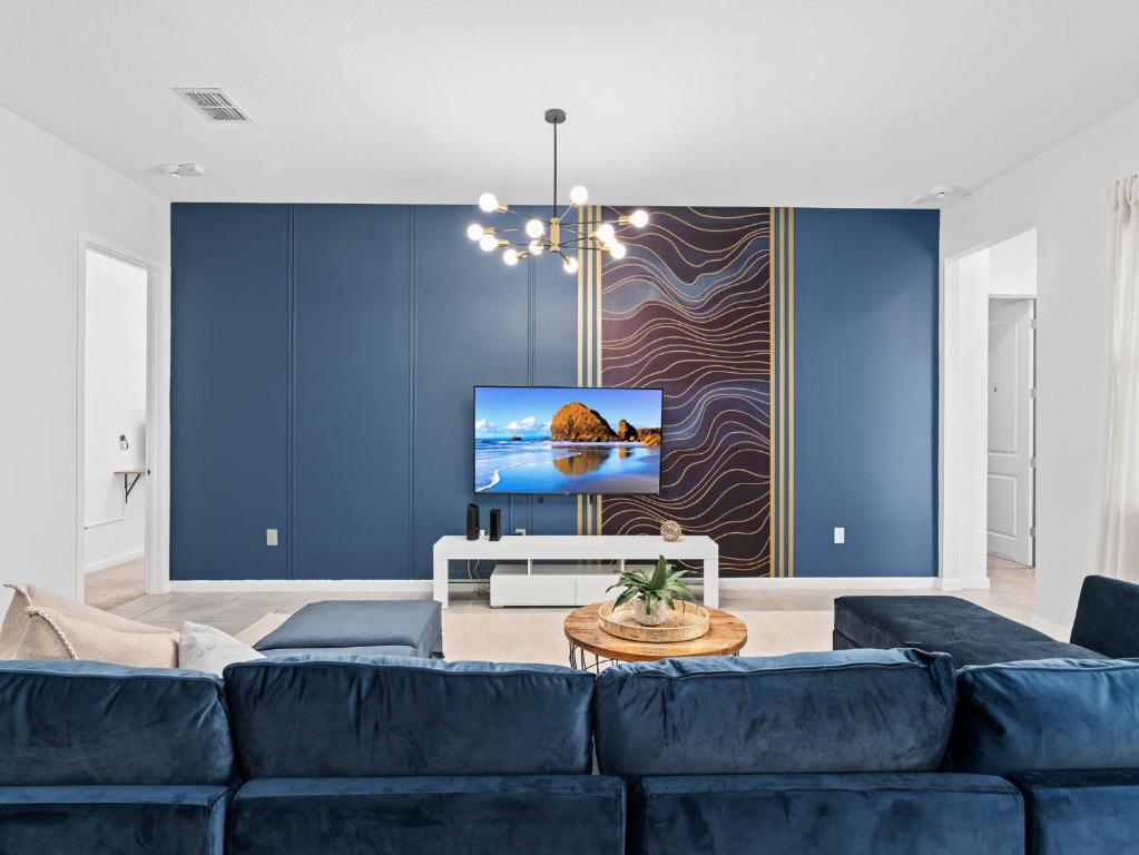 Una sala de estar con un sofá azul y un televisor en SUPER SPACE - 12BD 12BA - MANY ENSUITEs SLEEPs 38, en Kissimmee