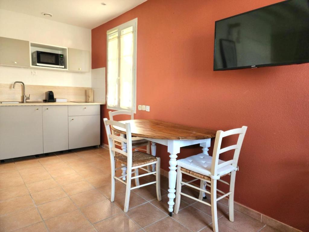une cuisine avec une table et des chaises ainsi qu'une télévision murale. dans l'établissement Jasses de Camargue, à Gallargues-le-Montueux