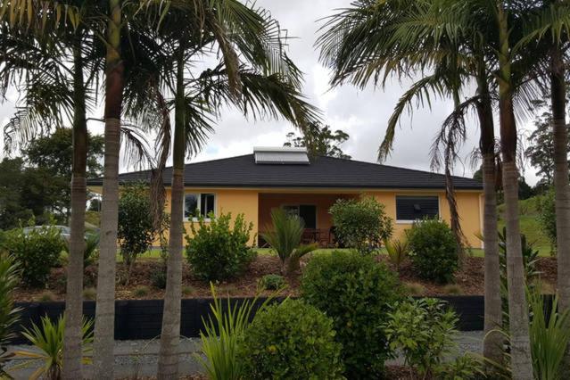 a yellow house with palm trees in front of it at Kerikeri Blue Chair B&B in Kerikeri