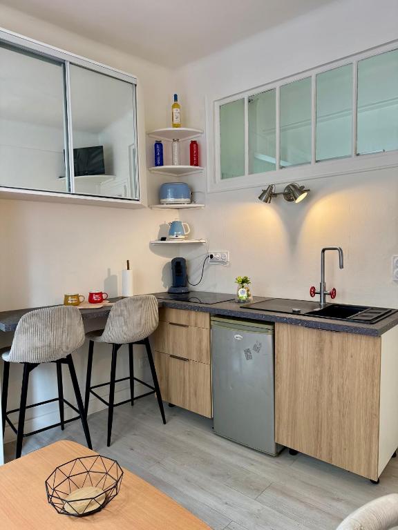 une cuisine avec un évier et un comptoir avec des tabourets dans l'établissement Studio cosy Paris 15, à Paris