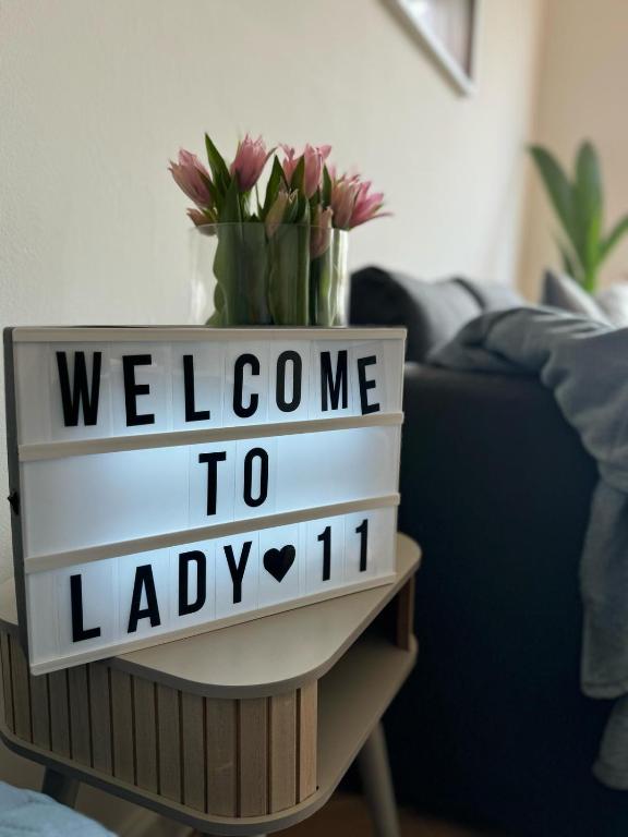 a welcome sign on a table with flowers on it at Apartament Lady Eleven in Gdańsk