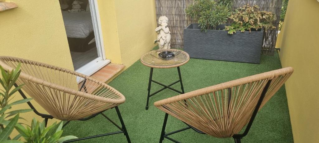 een patio met 2 stoelen en een tafel en een tafel bij Chambre La Palmeraie village naturiste in Cap d'Agde