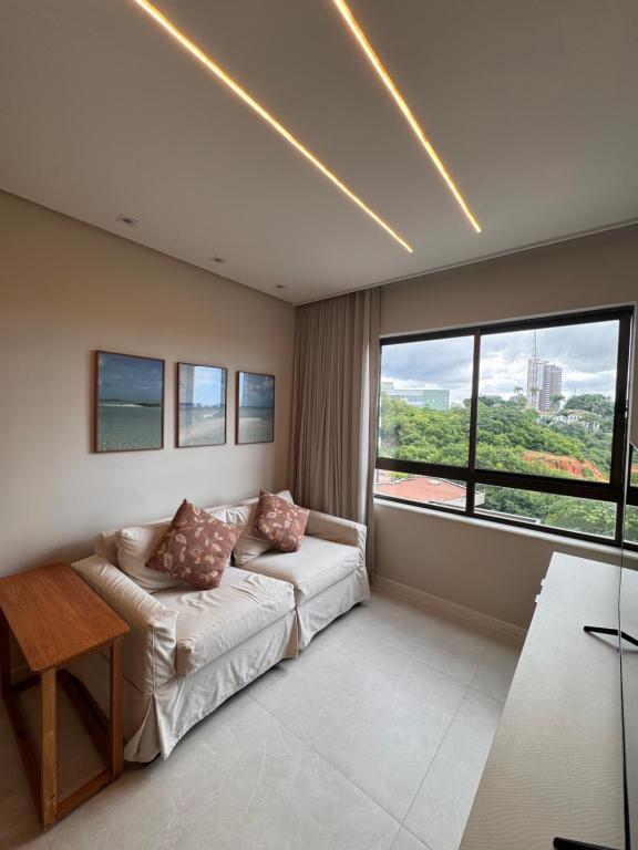 a living room with a couch and a large window at Cobertura com piscina privativa - Apart hotel in Salvador