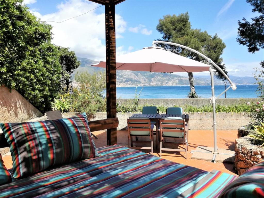 un patio avec une table, des chaises et un parasol dans l'établissement les pieds dans l'eau, à Roquebrune-Cap-Martin