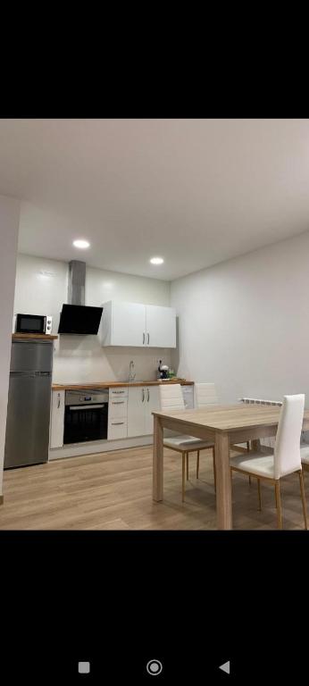 a kitchen with a wooden table and a table and chairs at Pensión Castineiras in Sarria