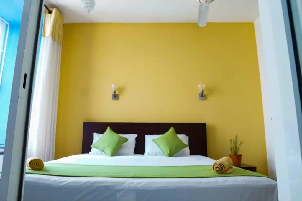 a bedroom with a large bed with a yellow wall at Rosemary Villa - Welegoda, Matara in Matara