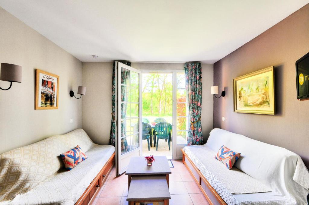- un salon avec deux canapés blancs et une table dans l'établissement La résidence du Lac - maeva Home - Appartement 2 pièces 5 personnes - Sélection MAE-2201, à Monflanquin