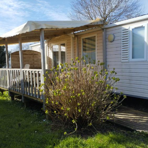 une petite maison avec une véranda et un parasol dans l'établissement Mobilhome 6 personnes, à Douarnenez