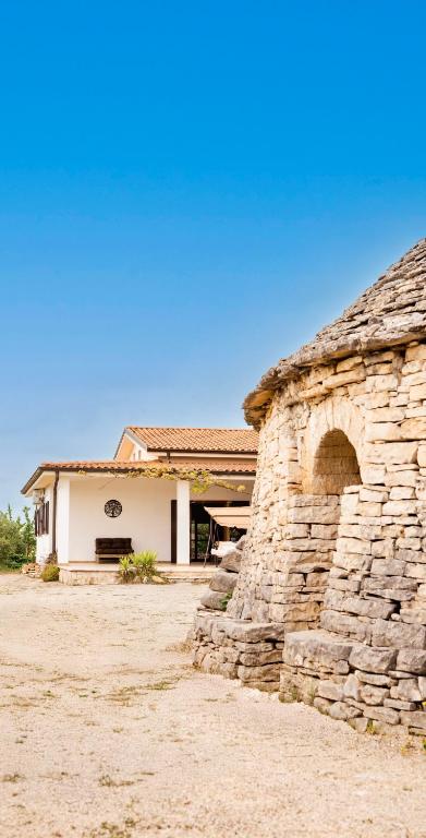 a building with a stone wall in front of it at Trullo Della Murgia - Villa in Castel del Monte