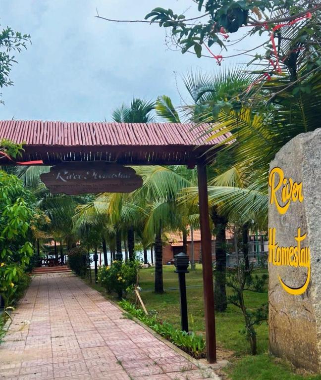 a sign for a rico hotel with palm trees at River Homestay in Hàm Tân