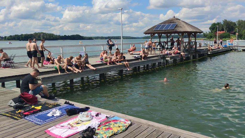 un grupo de personas sentadas en un muelle en el agua en Domek w Bogaczewie nad jeziorem Narie, en Bogaczewo