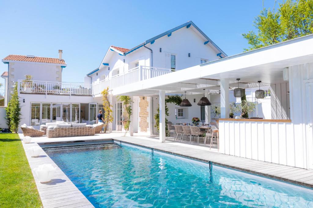 una casa bianca con piscina di fronte a una casa di Villa Les Peupliers avec piscine privée et sauna a Royan