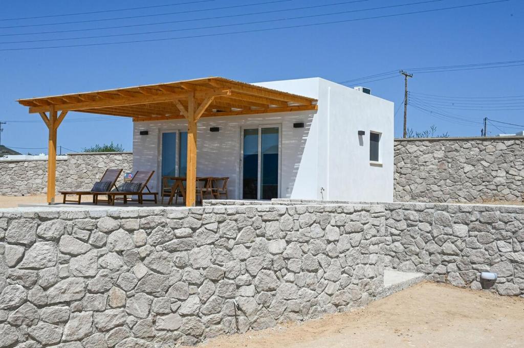 a house with a stone wall and a wooden roof at Porto Vista Milos in Adamas