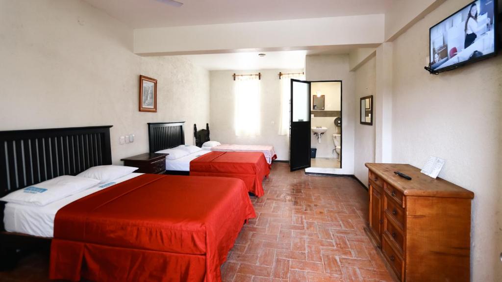 a hotel room with three beds and a flat screen tv at Hotel Guivá San Pablo in Hacienda Blanca