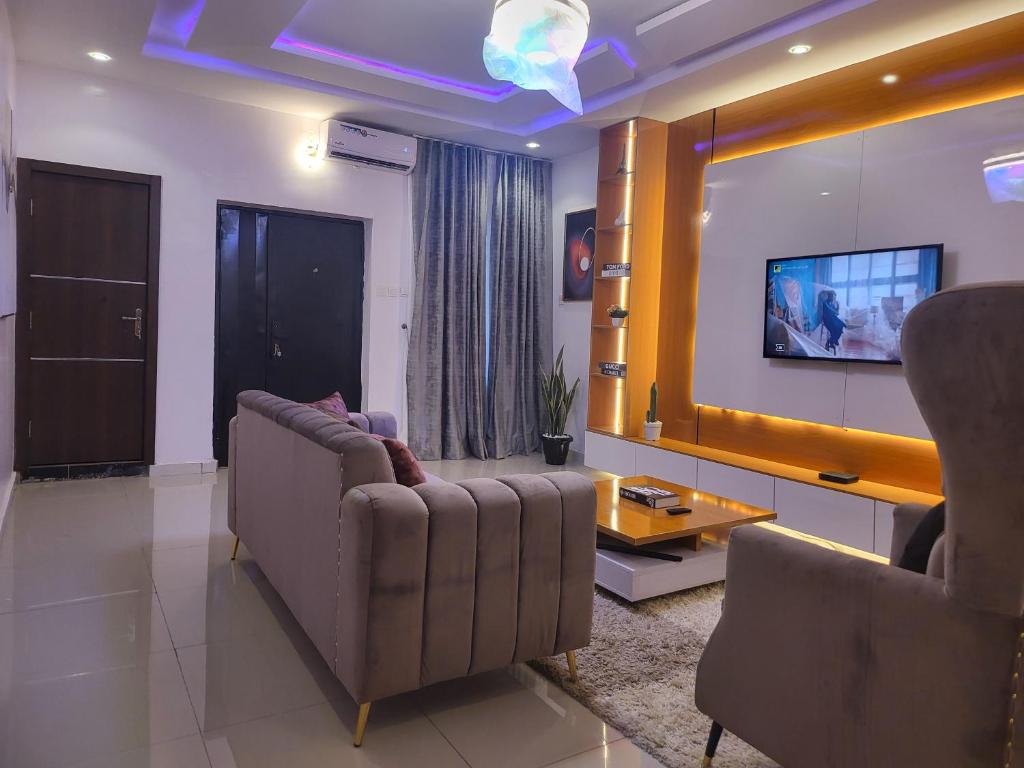 a living room with two chairs and a tv at Kings Heights Apartments in Ikeja