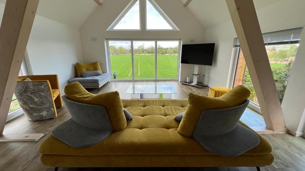 sala de estar con sofá amarillo y ventana grande en Les Villas du Ried, en Daubensand