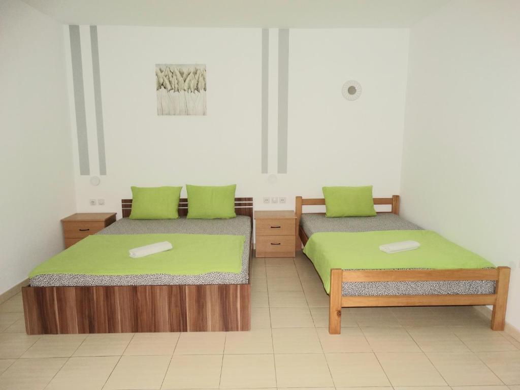 two beds in a room with green pillows on them at Vila Jenic in Soko Banja