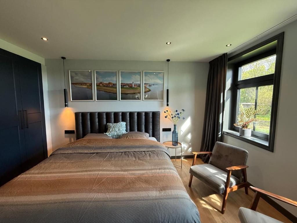 a bedroom with a large bed and a chair at Urk-Stay in Tollebeek