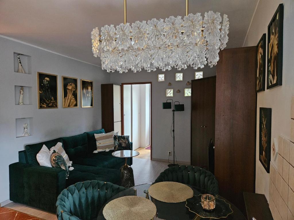 a living room with a green couch and a chandelier at GLAMOUR Apartment in Poznań