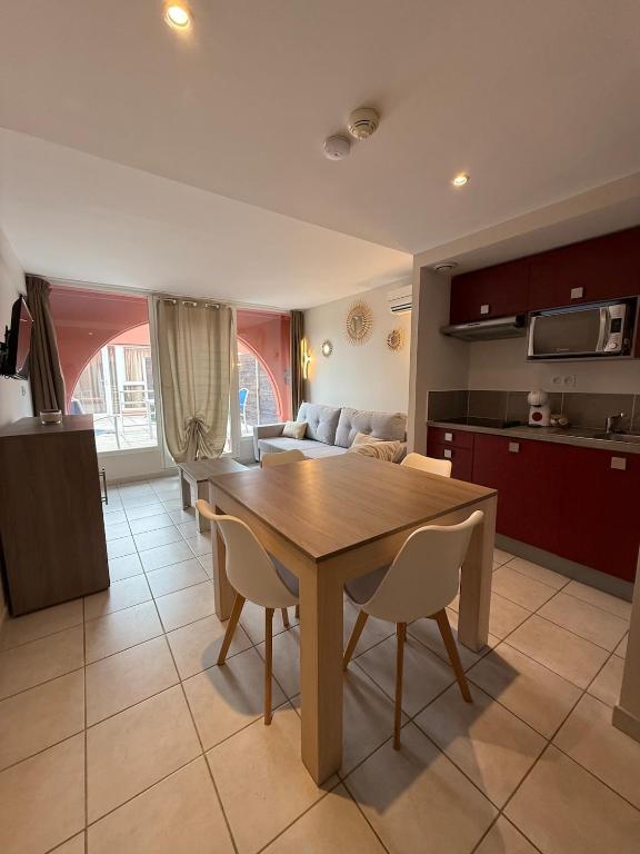 Il dispose d'une cuisine et d'un salon avec une table et des chaises en bois. dans l'établissement T2 Cap Agde Terrace Piscine, au Cap d'Agde