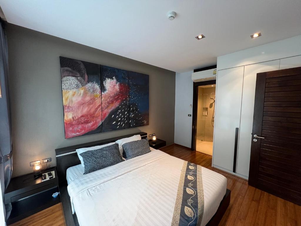 een slaapkamer met een bed en een groot schilderij aan de muur bij Emerald Terrace Condo 42- 1 Bed Pool in Patong Beach