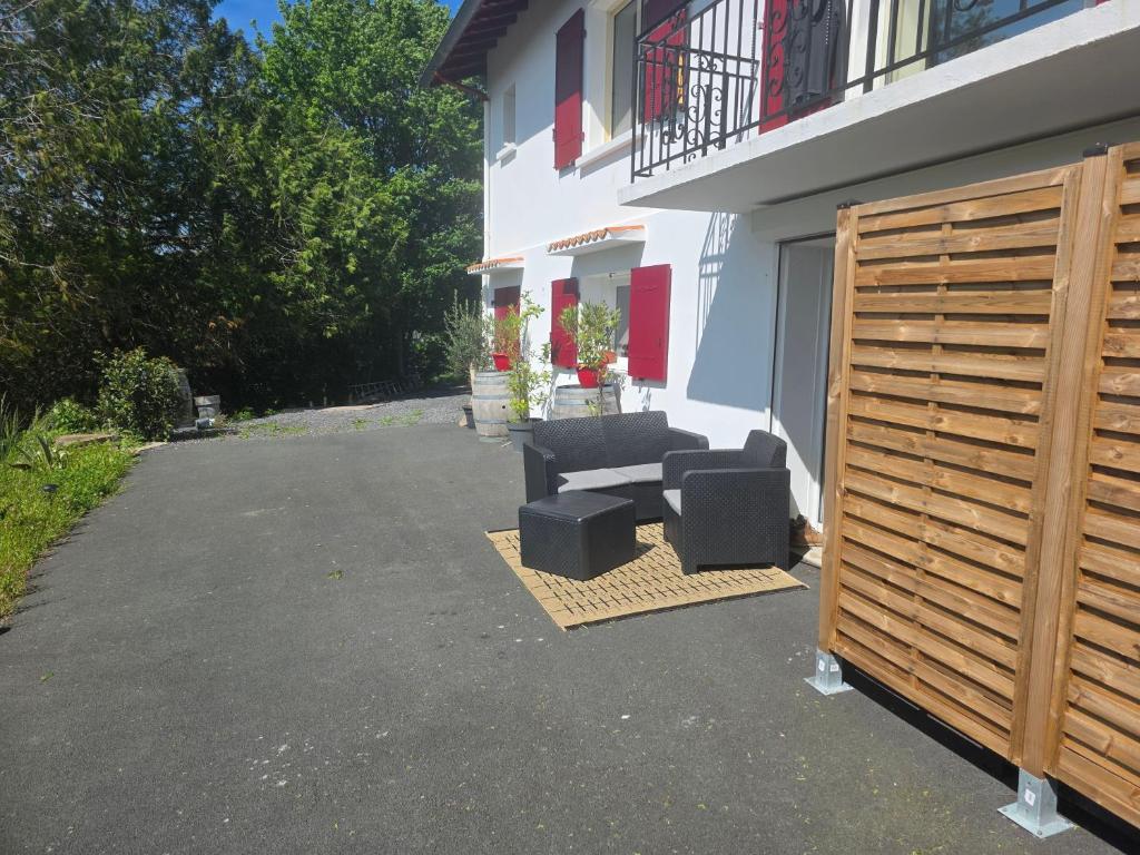 un patio avec deux chaises et un canapé à côté d'un bâtiment dans l'établissement Appartement tout confort, à Saint-Pierre-dʼIrube