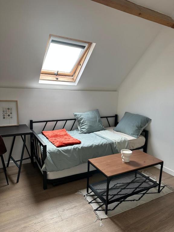 - un lit et une table dans une chambre avec fenêtre dans l'établissement Charmante studette chez l'habitant, à Poissy