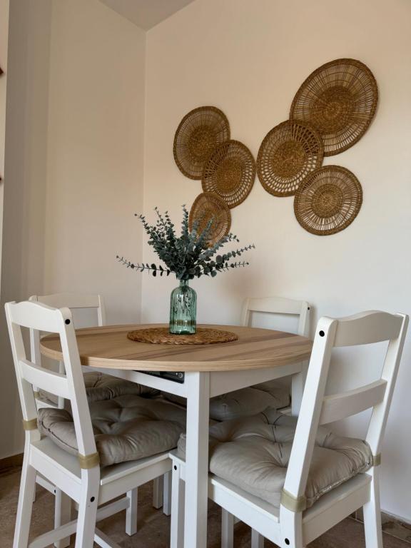 a dining room table with chairs and a vase with flowers at BARROSA CON ENCANTO, AC - WIFI - PARKING, Parejas y familias in Novo Sancti Petri