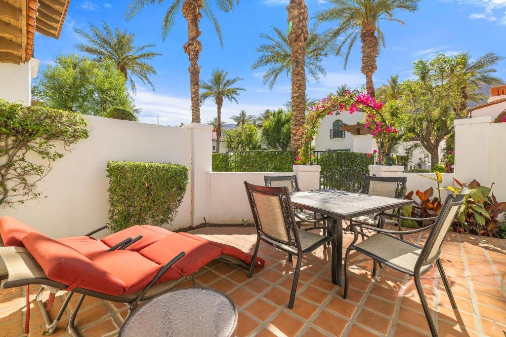 een terras met een tafel, stoelen en palmbomen bij SV104 Spacious Single Story 1 Bedroom Spa Villa in La Quinta