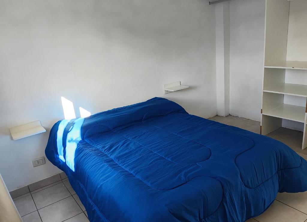 Una cama azul en una habitación blanca con estanterías en Depto Civora 4, en Villa Regina