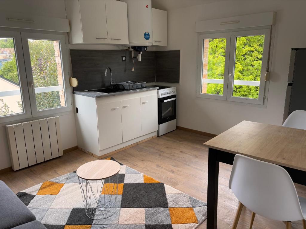 a kitchen with white cabinets and a table and chairs at Appartement T3 - Plage à 500m in Saint-Nazaire