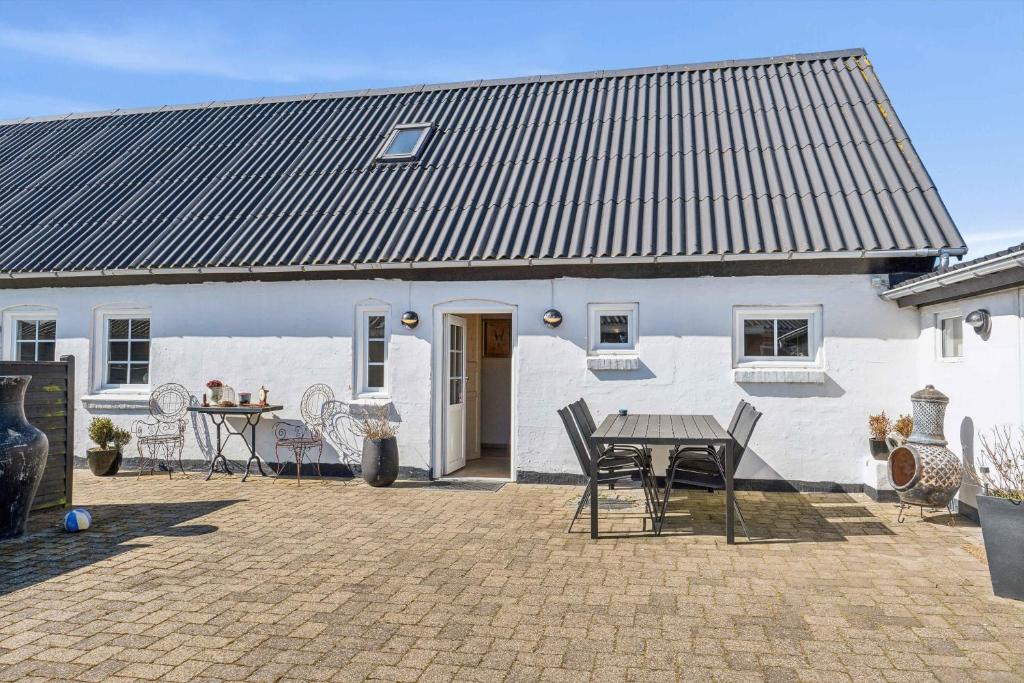 HarboørにあるCozy Holiday Home In Harboøreのパティオ(テーブル、椅子付)が備わるホワイトハウスです。