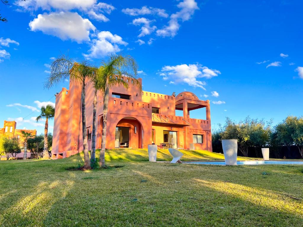 马拉喀什Villa Zeen Garden的一座种植了棕榈树的橙色建筑