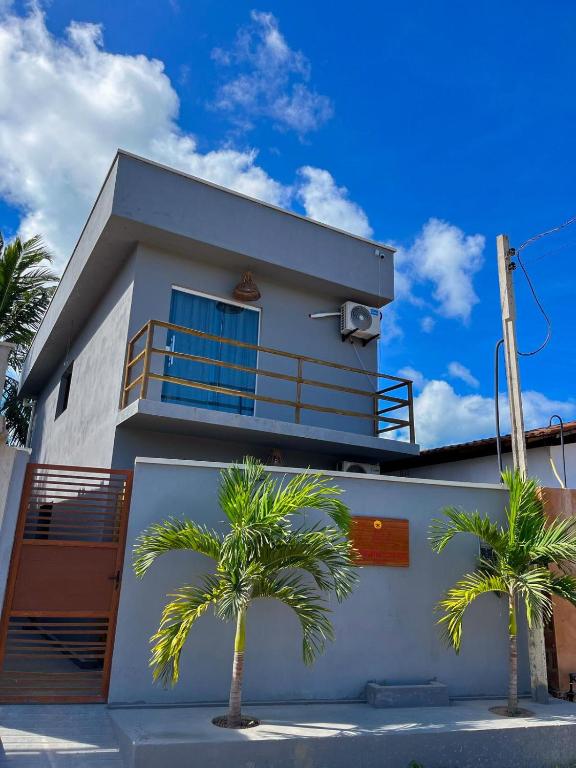 una casa bianca con palme di fronte di Flats Rota dos Corais a São Miguel dos Milagres